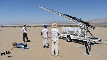 Photograph of team elevating rocket to a vertical orientation on launch rail