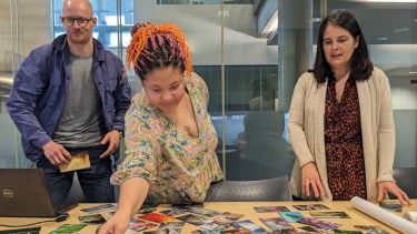 3 people looking at a range of colourful photos on the table