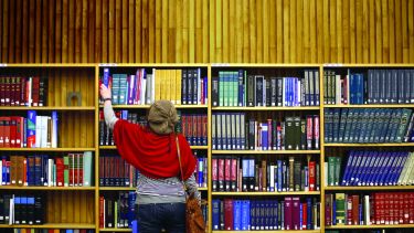 A photo of someone reaching for a book in the library