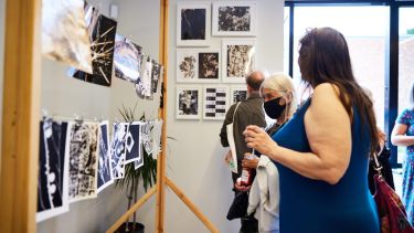Photograph of an art exhibition with visitors looking at the art works