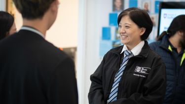 A female member of our security services team in her uniform smiling at two other people who have their backs to the camera