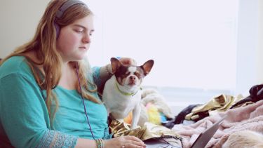 A young woman wearing headphones with her dog