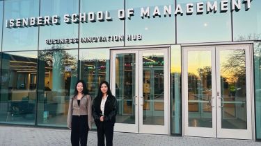 2 PhD students stood outside Isenberg School of Management.