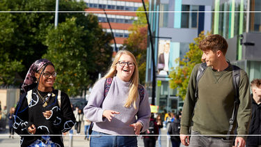 Photograph of three people walking outside Jessop West building in the sunshine
