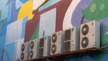 A colourful building wall with AC units
