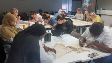 A group of students writing on tote bags as part of a Wellbeing Wednesday craft afternoon