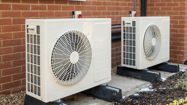two heat pumps outside of a modern brick house 