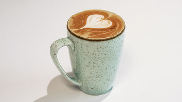 Latte in a tall white mug with heart shaped latte art