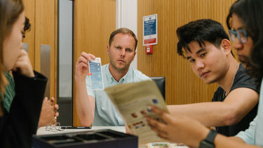 Image of Stephen Allen playing a board game with students during MBA Induction Week
