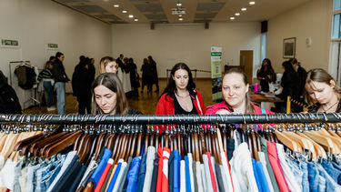 A group of girls browsing a rail full of clothes 