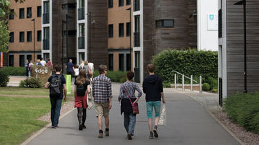 A group of five people walking down a path through the Endcliffe student residences