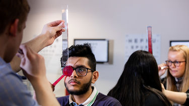 An ophthalmology student gets their eye examined by a fellow student