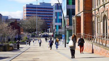 People walking down the street of red brick and modern buildings