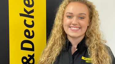 Lucy Hattersley, an apprentice from the AMRC Training Centre stood next to a sign for the company Black & Decker