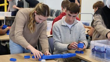 Two first year students (a male and a female) building a bridge from blue Duplo bocks 