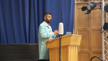 Dr Senthorun Raj at the front of the lecture hall behind a lectern speaking about their work.