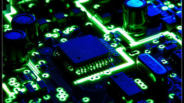Circuit board lit up in blue and green.