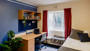 Student accommodation bedroom with a single bed, desk, large window with seating ledge underneath