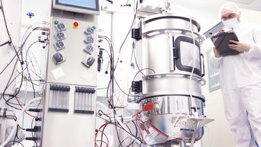 A person standing next to a bioreactor.