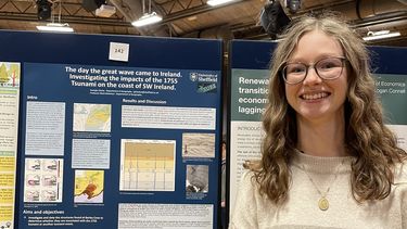 Georgia Clarke smiling next to her research poster