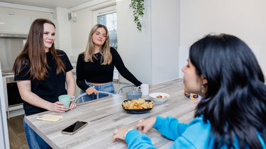 A group of girls sat at a kitchen table having a discussion