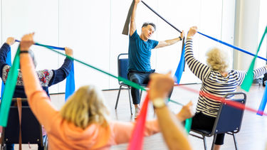 older adults in seats stretching as part of a group exercise class