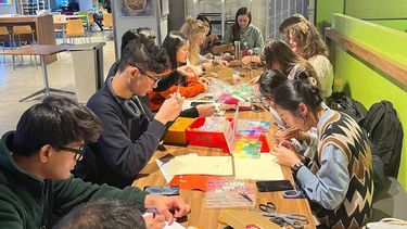 A large group of students enjoy craft activities at a long table