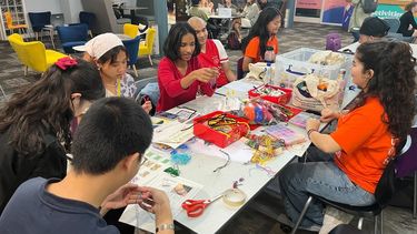 A busy table surrounded by people involved in crafts and games