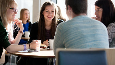 Photograph of a group of students sat at a table in a cafe. 