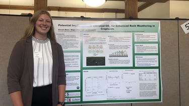 A photo showing summer intern Hannah Maher presenting her findings in the form of a poster at the Illinois Student Research Program Alliance Symposium