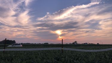 A photo showing a purple and gold sunset with light clouds at the farm in Illionois