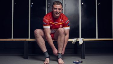 Rugby player Blake Broadbent putting his sock on 