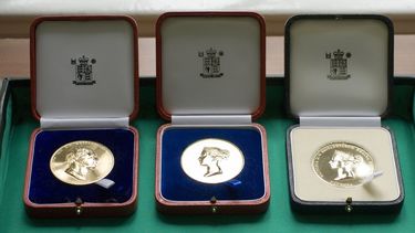 Three gold medals inside open cases
