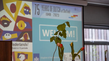 screen saying welcome to the event with two bottles of tulips and a tree in the foreground