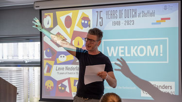 Wouter Deprez lifting his right hand while speaking with text in his left hand