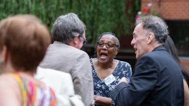 Two women and two men laugh together outside during a reunion event. 