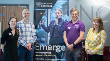 Team of staff standing by Emerge banner for photo