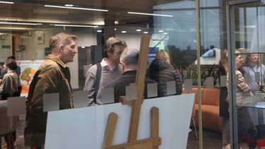 View from the Digital Commons to the exhibition space in the IC, with people looking at the artefacts
