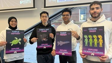 Four students holding posters for video games they have developed