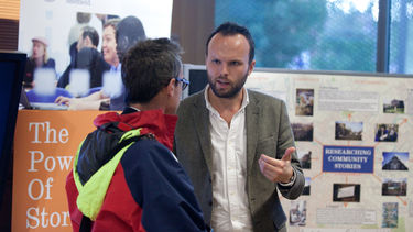 Tutor talks to another tutor in front of an academic poster