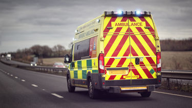Ambulance driving on a road under a moody grey sky