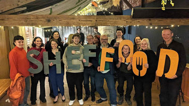 Group celebrating ShefFood's silver award from Sustainable Food Places, holding up letters spelling Sheffood