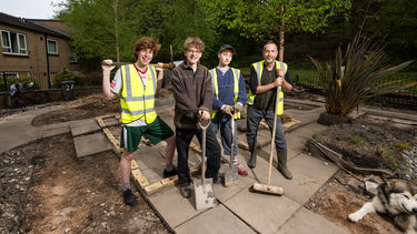 Four students and volunteers stood at the Scraith Wood Community Garden with spades and gardening tools