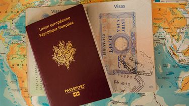 A french passport on top of a world map.