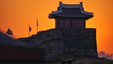 Traditional Korean temple with sunset behind it