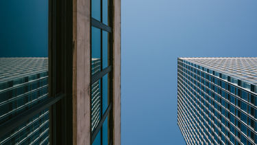Two angular buildings as seen from below - with clear blue sky in background