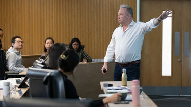 A man presenting a lecture theatre full of students.