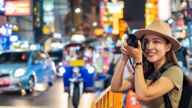 A busy street in Bangkok. A person is taking a photo with a camera.