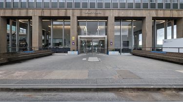 The top 2 steps and broken paving leading to an automatic door at the front of our Arts Tower building which has a lot of glass and some concrete