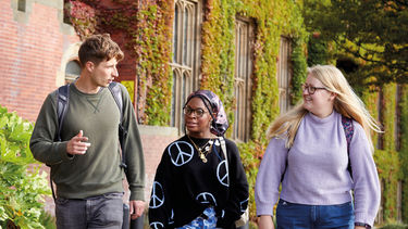 Students walk outside a red-bricked university building